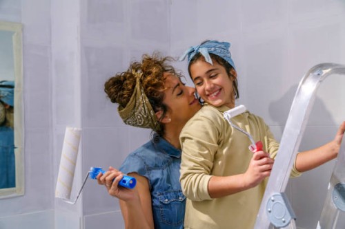 mother and daughter painting a wall of her house together - home decoration stock pictures, royalty-free photos & images