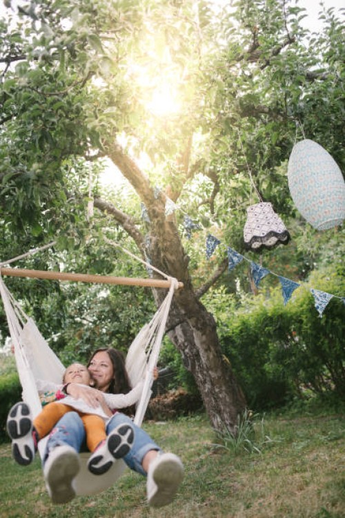mother and daughter smiling while swinging on hammock in backyard - garden decoration stock pictures, royalty-free photos & images
