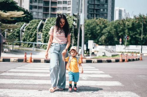 mother and son carrying rucksack walking on zebra crossing on way to school - fashion stock pictures, royalty-free photos & images
