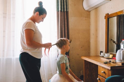 mother braids her little daughter in front of the mirror in bright living room. family weekend. profile view - hairstyle stock pictures, royalty-free photos & images