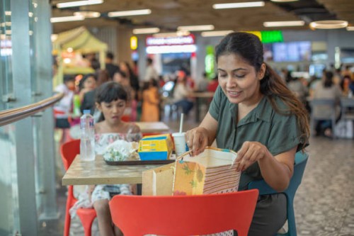 mother checking shopping bags on chair while daughter eating fast food at food court - junk food stock pictures, royalty-free photos & images