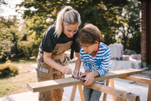 mother measuring wooden plank by son at construction site - home decoration stock pictures, royalty-free photos & images
