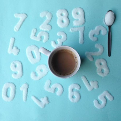 mug of coffee surrounded by numbers drawn in sugar - junk food stock-fotos und bilder