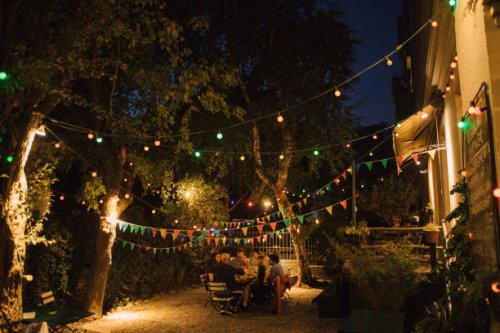 multi-ethnic friends enjoying dinner party in illuminated backyard - garden decoration stock pictures, royalty-free photos & images
