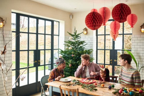multi racial family talking at dining table at christmas - home decoration stockfoto's en -beelden