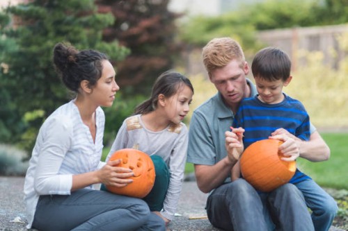 multiethnic family carving pumpkins together - garden decoration stock pictures, royalty-free photos & images