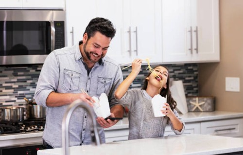 multiracial girl, father eat chinese take out in kitchen - junk food stock pictures, royalty-free photos & images