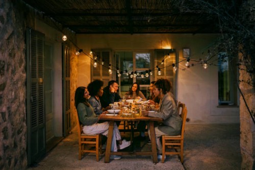 multiracial male and female friends sitting at dining table in patio during dinner party - garden decoration stock pictures, royalty-free photos & images