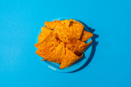 nachos on a blue colored plastic plate - junk food stock-fotos und bilder