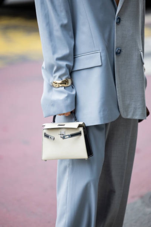 Nadia Phillips wears grey blue two tone oversized blazer, golden bracelet, Hermes bag, wide leg pants outside Altuzarra during New York Fashion Week...
