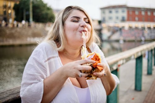 nahaufnahme einer frau, die draußen fast food isst und genießt - junk food stock-fotos und bilder