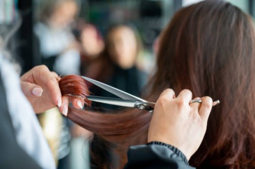 nahaufnahme eines nicht wiederzuerkennbaren friseurs, der einer kundin die haare schneidet - hairstyle stock-fotos und bilder