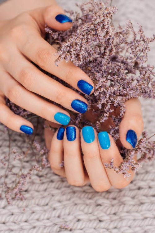 nails of women covered in blue lacquer different shades with rhinestones and with flowers in his hand. - nails art stock pictures, royalty-free photos & images