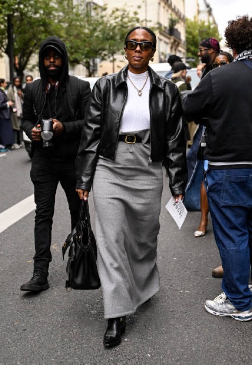 Nicole Martine Chapoteau is seen wearing a black faux leather jacket, white shirt, gray skirt, black and gold buckle belt and black shoes with black...