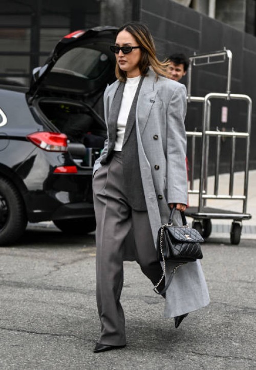 Nicole Warne is seen wearing a light gray coat, gray suit, white top and black sunglasses with black chain Chanelbag outside the Jason Wu show during...