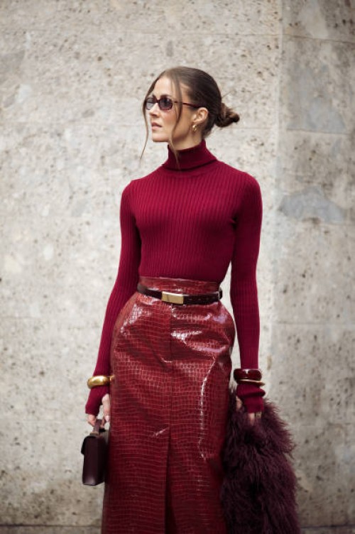 Nina Sandbech wears burgundy pencil skirt with reptile print, burgundy turtleneck, belt, burgundy bag, golden statement bracelets during the Milan...