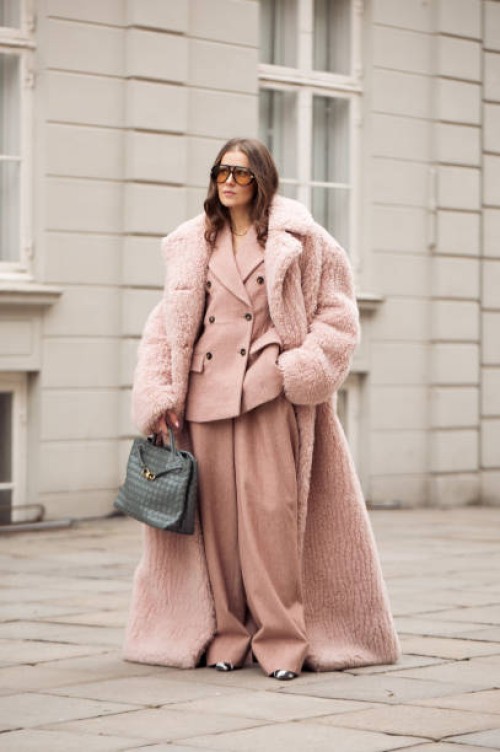 Nina Sandbech wears dust pink suit, Stella McCartney long dusty pink ground touching oversized fake fur coat, orange sunglasses and grey bag during...
