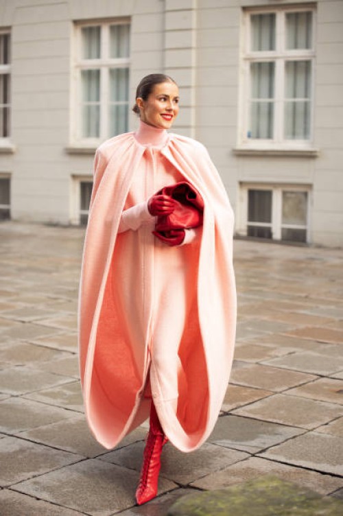 Nina Sandbech wears pink coat/dress, red pointy leather shoes, red leather gloves, red leather bag during the Copenhagen Fashion Week Autumn/Winter...