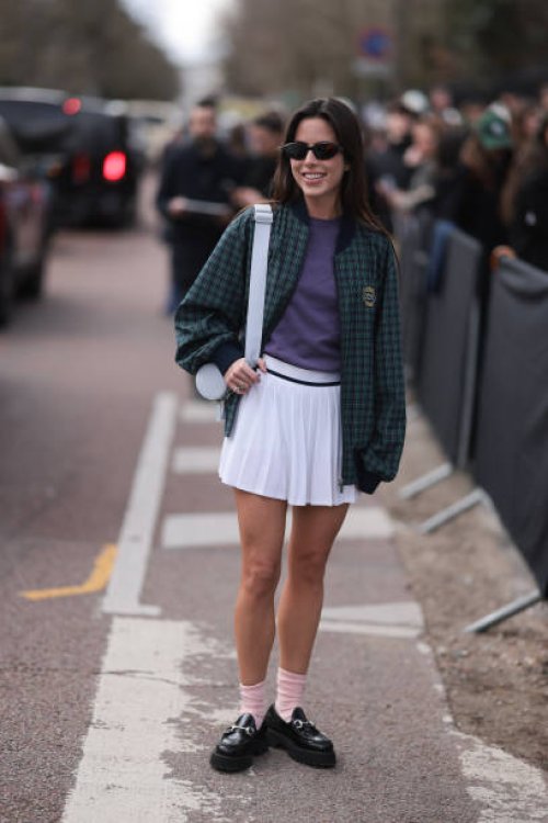Nina Urgell Cloquell seen wearing a white tennis skirt, green and black checkered Lacoste jacket, purple shirt, black shades, black leather loafer,...