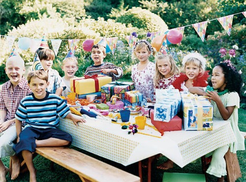 nine children sitting at a table at a birthday party - garden decoration stockfoto's en -beelden