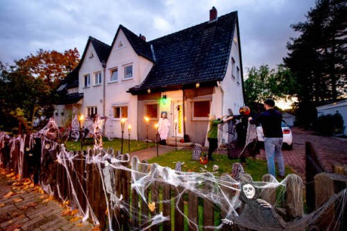 October 2020, Lower Saxony, Hanover: Marleen Salewski and Julian Witte decorate a cross with artificial cobwebs in their front garden in the Bothfeld...