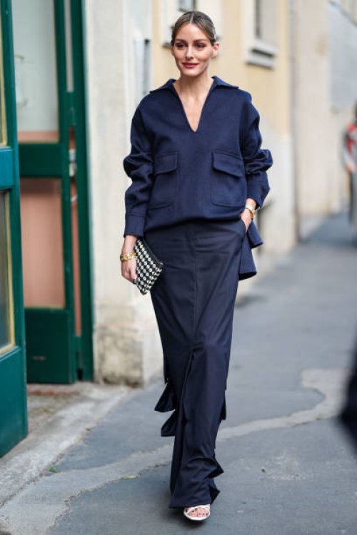 Olivia Palermo wear navy blue long sleeve shirt, black loose low slit maxi skirt, black white polka handbag, gold chain necklace, white open toe...