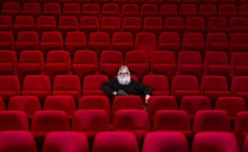 one man with white beard sits in empty cinema or theatre with comfortable red seats - concert stock pictures, royalty-free photos & images