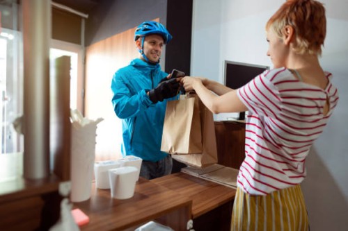 one woman, fast food worker, giving bags with prepared meals to a delivery man - junk food stock pictures, royalty-free photos & images