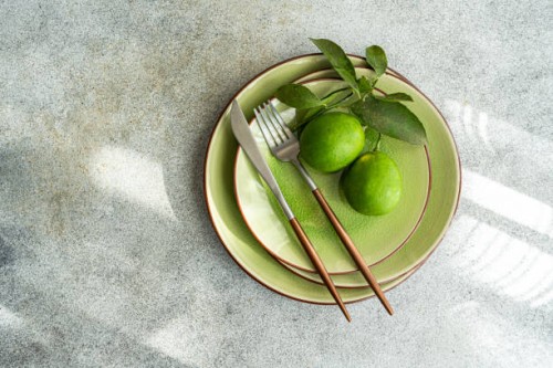 overhead view of a place setting decorated with two freshly picked limes - home decoration stock pictures, royalty-free photos & images