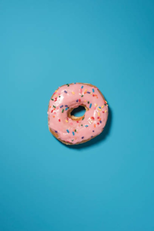 overhead view of doughnut on blue background - junk food stock pictures, royalty-free photos & images