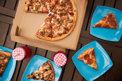 overhead view of pizza with blue plates and drinks on wooden table - junk food stock pictures, royalty-free photos & images