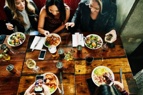 overhead view of smiling female friends sharing lunch in restaurant - food stock pictures, royalty-free photos & images