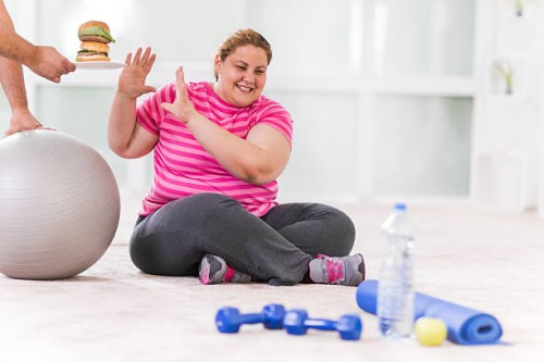 overweight woman refusing hamburger. - junk food stock pictures, royalty-free photos & images