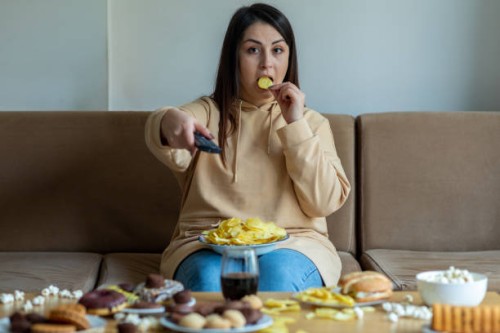 overweight woman sit on the sofa with junk food - junk food stock pictures, royalty-free photos & images