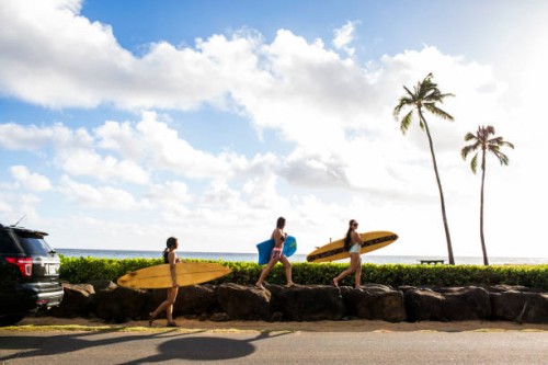 pacific islander surfers carrying surfboards on rock wall - travel stock-fotos und bilder