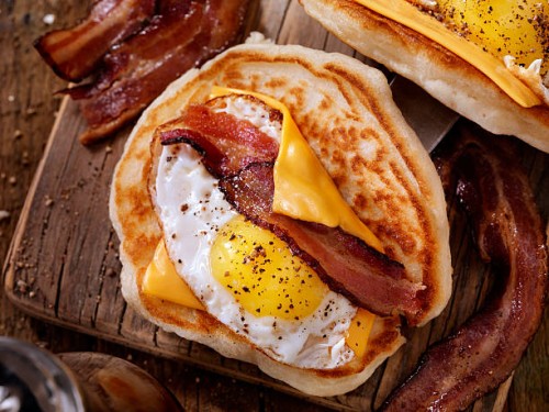 pancake breakfast taco with suny side up eggs, bacon, cheese - junk food stock pictures, royalty-free photos & images