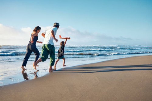 parents running behind a boy running straight ahead with a model airplane held high in one hand. - travel stock pictures, royalty-free photos & images