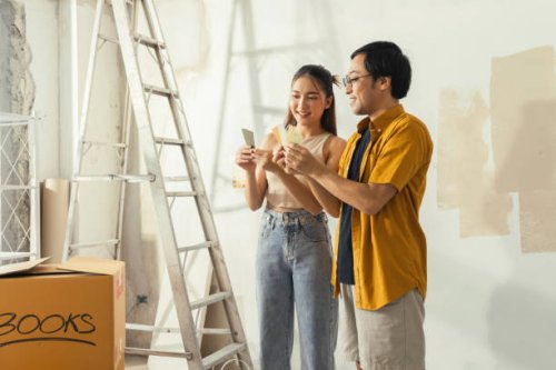 peaceful asian cheerful couple young man and woman smiling sit together on floor painting white wall with roller during renovation house relocation in new apartment happy couple painting walls - home decoration stock pictures