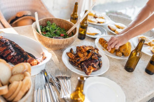 people's hands reaching for food on a picnic table at a barbecue party - food stock pictures, royalty-free photos & images