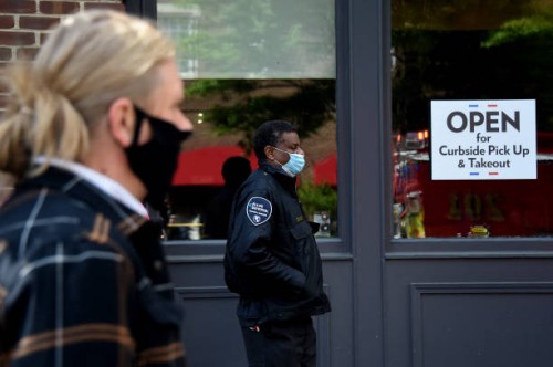People wearing face masks wait in line in front of a restaurant open for takeout amid the coronavirus outbreak on May 11, 2020 in Alexandria,...