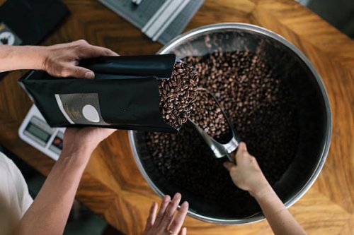 people working in roastery filling package - coffee stockfoto's en -beelden