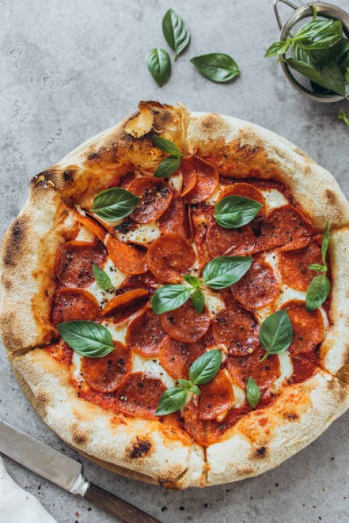 pepperoni pizza garnished with basil leaves - junk food stock pictures, royalty-free photos & images