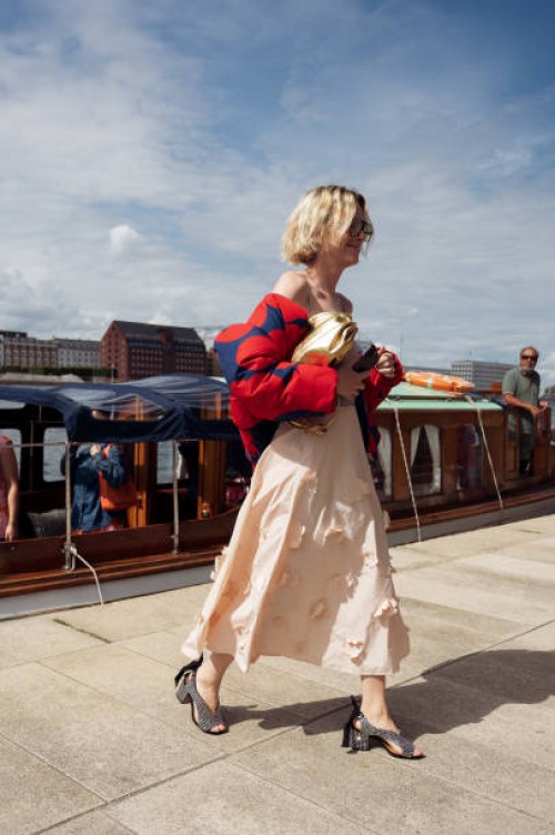 Pernille Rosenkilde wears peach or beige skirt, red and blue puffy jacket and golden bag at VIP guest trip with a boat to the Marimekko show during...