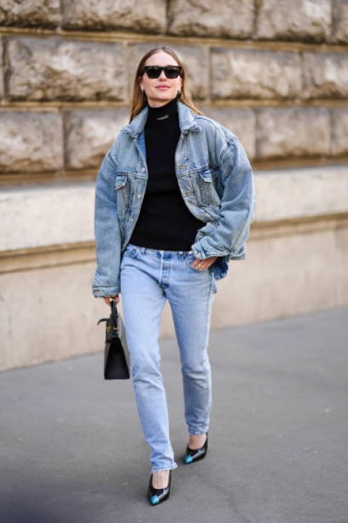 Pernille Teiba wears black sunglasses, diamonds earrings, a black turtleneck pullover from Balanciaga, a blue faded oversized jacket, blue faded...