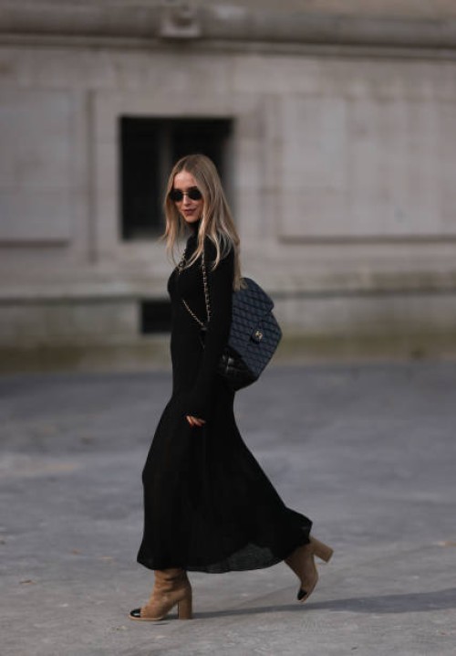 Pernille Teisbaek is seen wearing a long black dress with brown suede boots, a black Maxi leather Chanel handbag and black sunglasses during the...