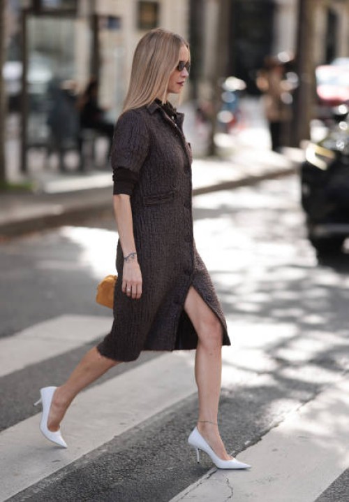 Pernille Teisbaek is seen wearing oval sunglasses with Havana frame from Miu Miu, a knee-length short-sleeved dark brown structured dress with collar...
