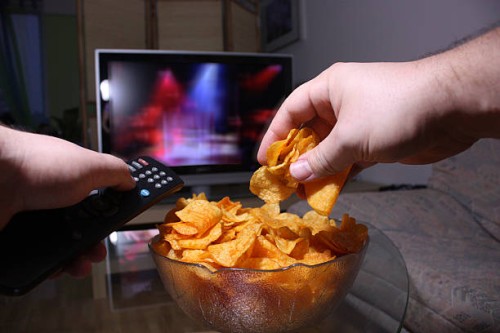 person changing the tv station and reaching for potato chips - food stock pictures, royalty-free photos & images