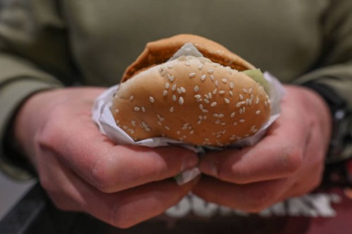 Person enjoys a burger inside a fast food restaurant, on March 28 in Krakow, Poland.