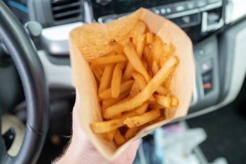 Person's hand holds a takeout french fry container in an automobile in Concord, California, November 25, 2022.