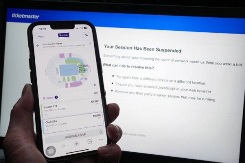 Person who has had their Ticketmaster session suspended on a laptop, as the StubHub website is displayed on a phone, detailing information about...